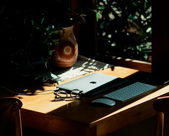 Mesa de trabalho com laptop, teclado e planta